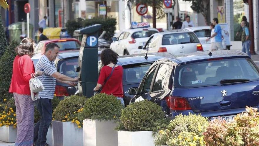 Un grupo de usuarios de la zona azul obtiene su tique en un parquímetro de Vigo. // José Lores