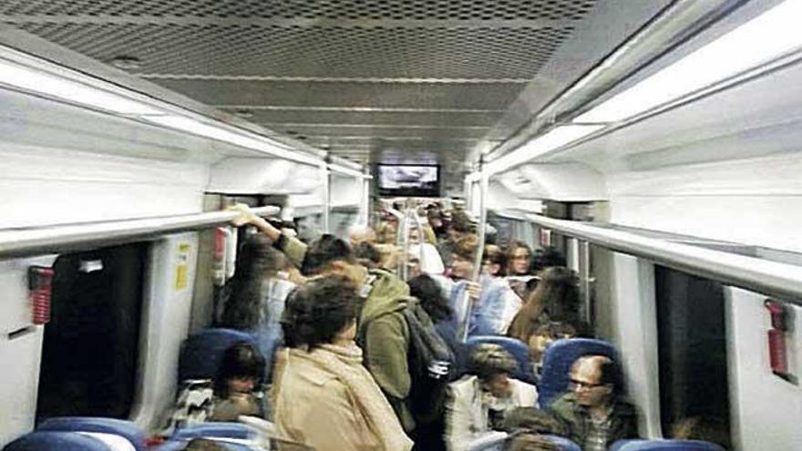 Interior de un vagón del tren repleto de usuarios.