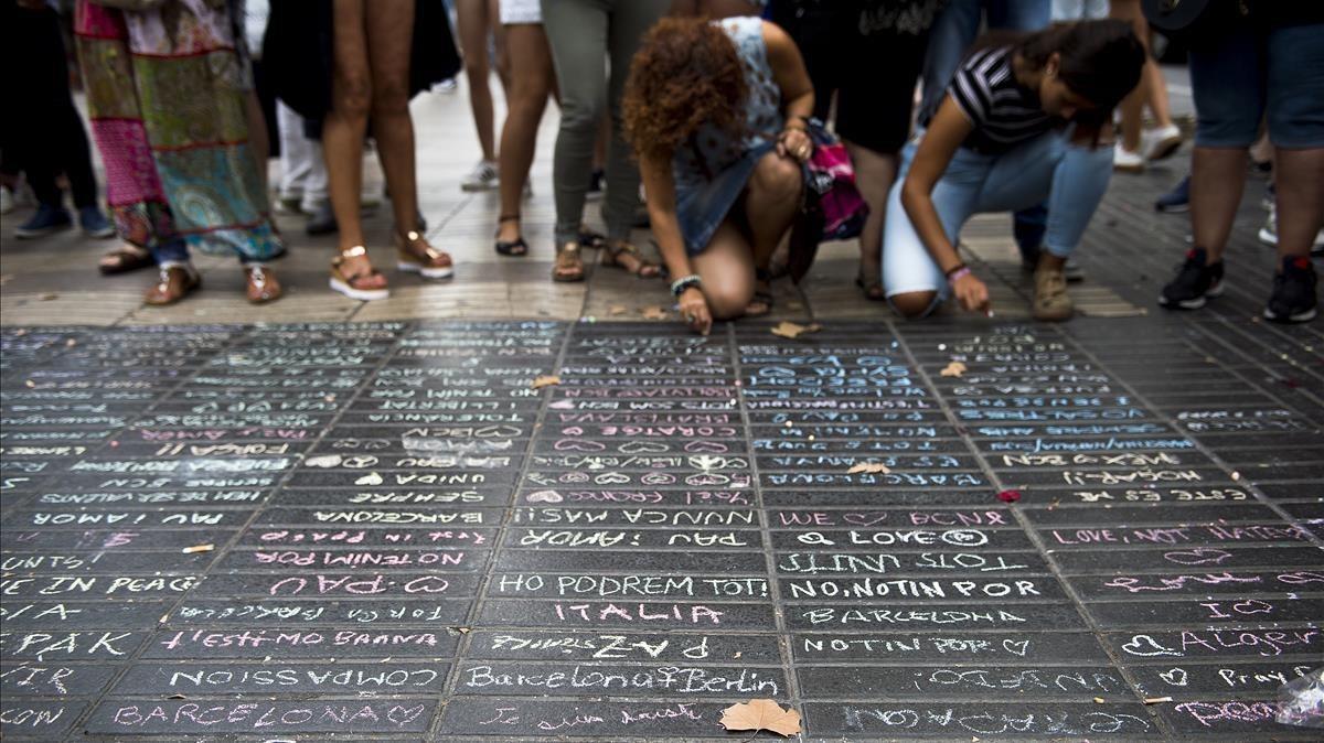 Los transeúntes escriben sus condolencias con tizas sobre el pavimento de la Rambla el 19 de agosto de 2017. 