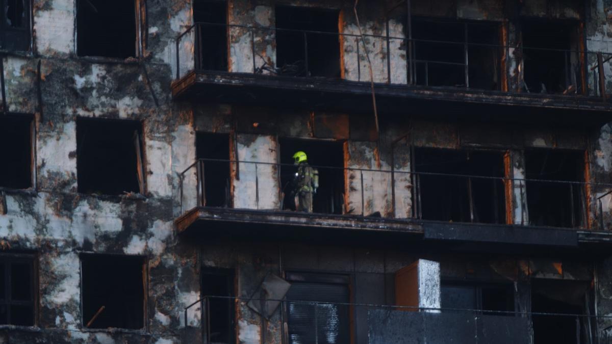 Un bombero inspeccionando el edificio incendiado en Valencia en el día de ayer.