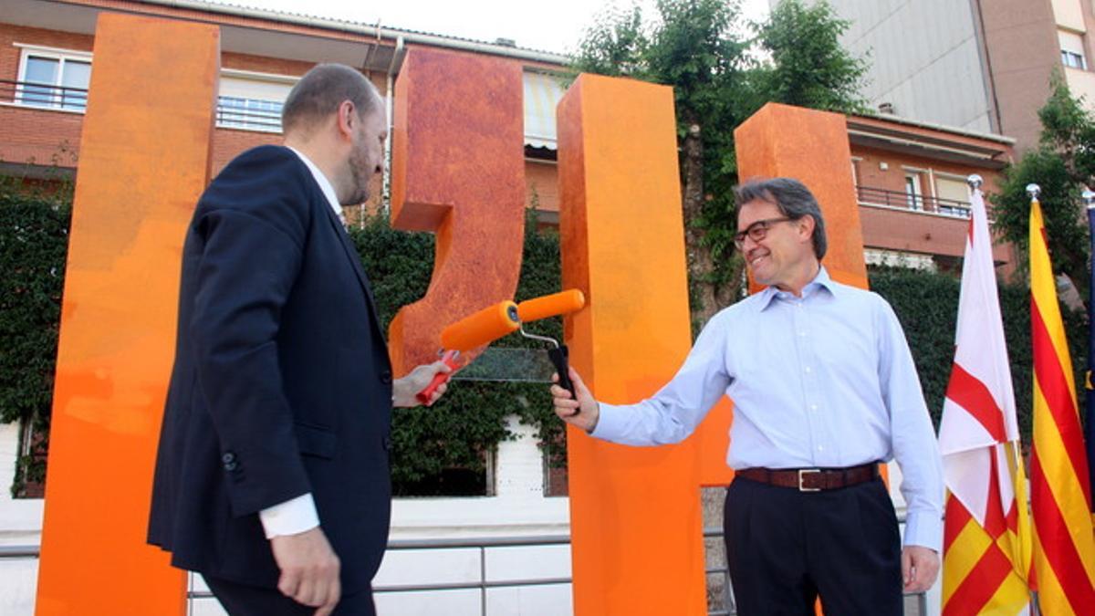 El presidente de la Generalitat, Artur Mas, y el candidato de CiU en L'Hospitalet de Llobregat, Jordi Monrós, con los rodillos de pintura naranja.