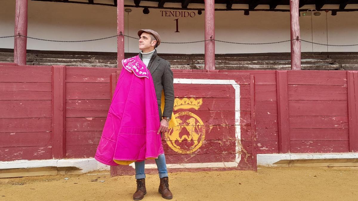 Félix de Carboneras posa en la plaza de toros de Toro con el capote con la esclavina bordada con notas musicales.
