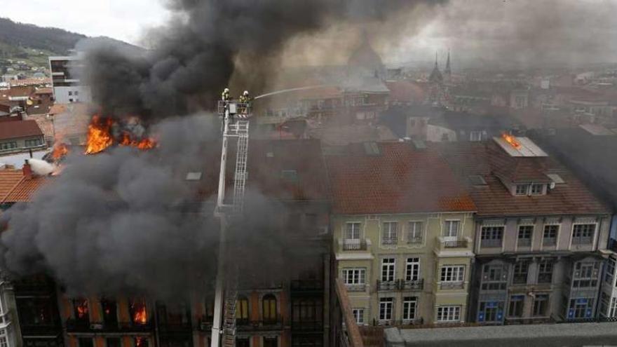 Los bomberos tratan de sofocar el extinguir el fuego en un edificio de la calle Uría, en Oviedo.