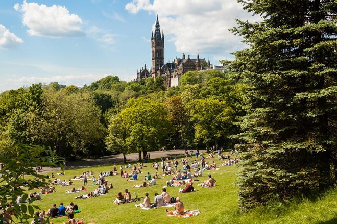 Vista del Parque Kelvingrove con personas y de la Universidad de Glasgow