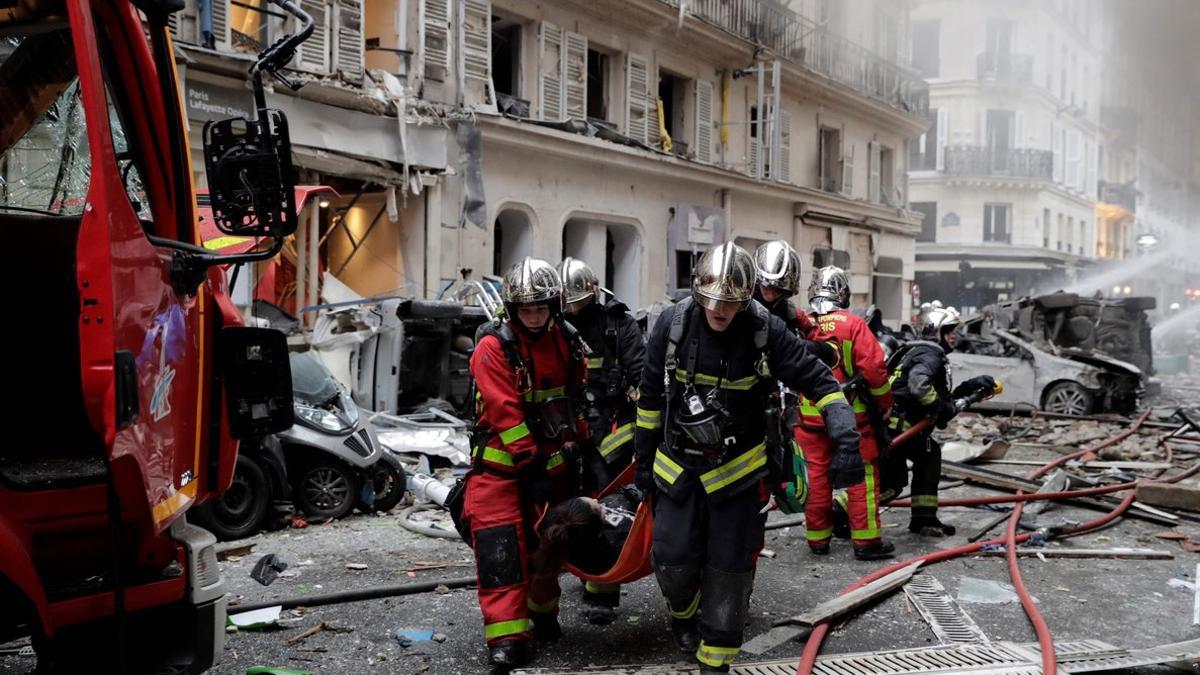 Los bomberos trasladan a una herida en la explosión en una panadería en París, este sábado.