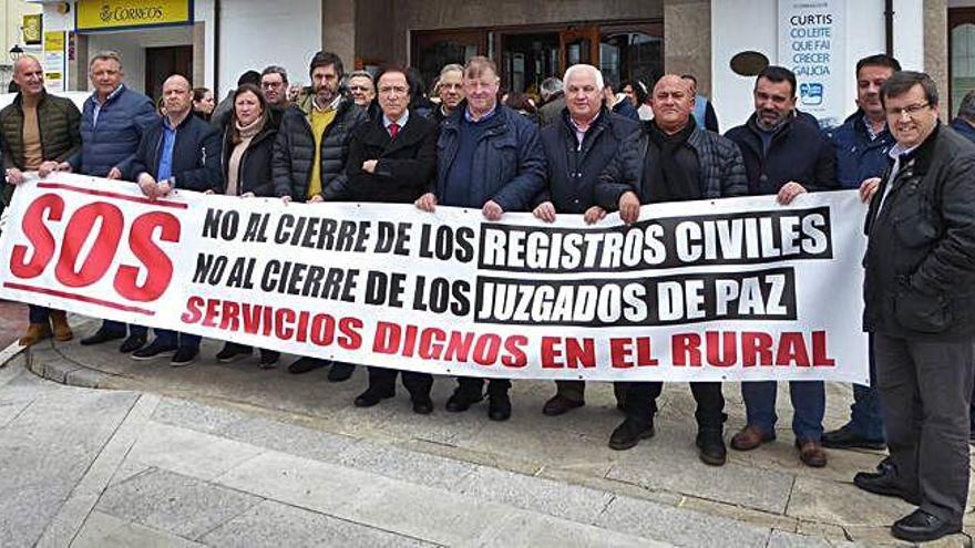 Alcaldes de doce concellos de la comarca y de Lugo, junto a secretarios de juzgados de paz y registradores, ayer ante el Concello en Teixeiro.