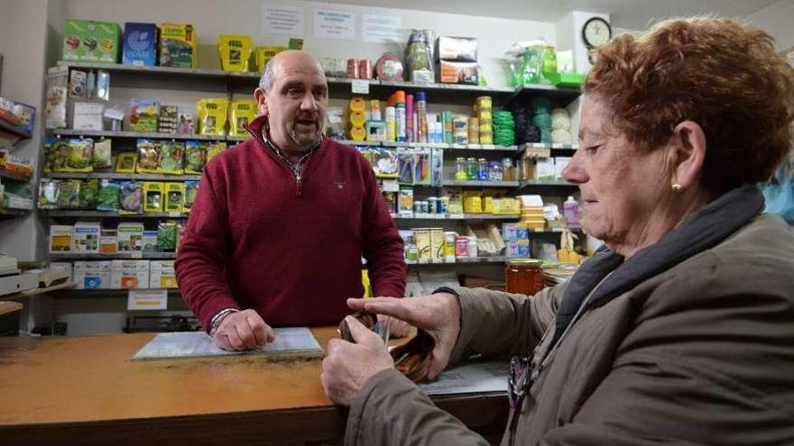 Roberto Sousa atiende a una mujer en su tienda de productos agrícolas.