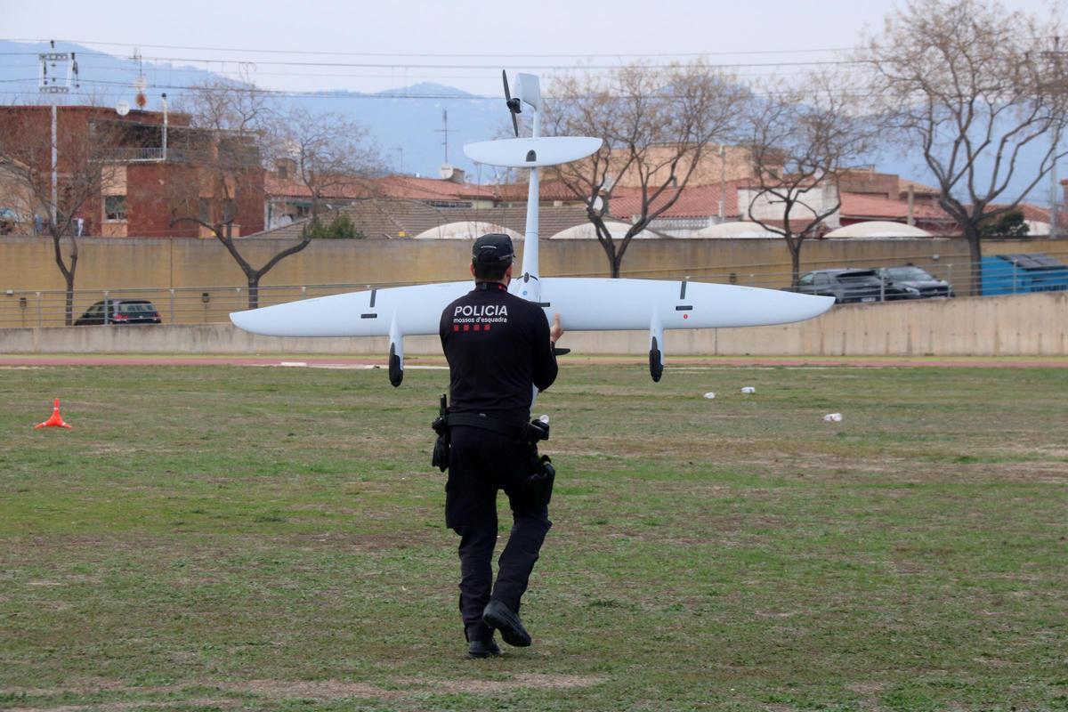 Un agent dels Mossos d'Esquadra trasllada el nou dron d'ala fixa per enlairar-lo