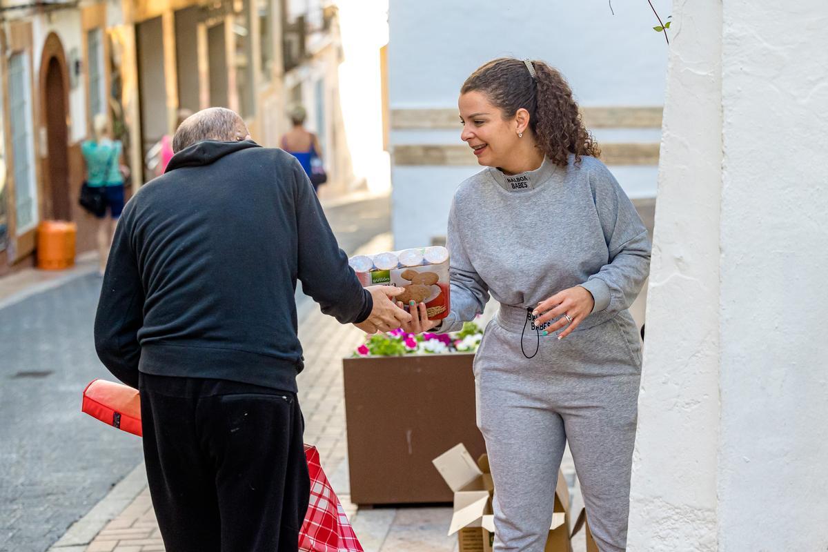 Una voluntaria entrega a un usuario de Cáritas distintos productos de alimentación.