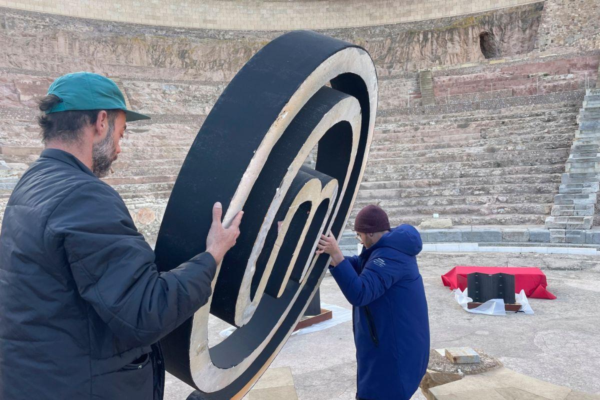 El Teatro Romano de Cartagena se convirtió en el plató de 'MasterChef'; en la imagen, dos trabajadores sostienen el logo del programa.