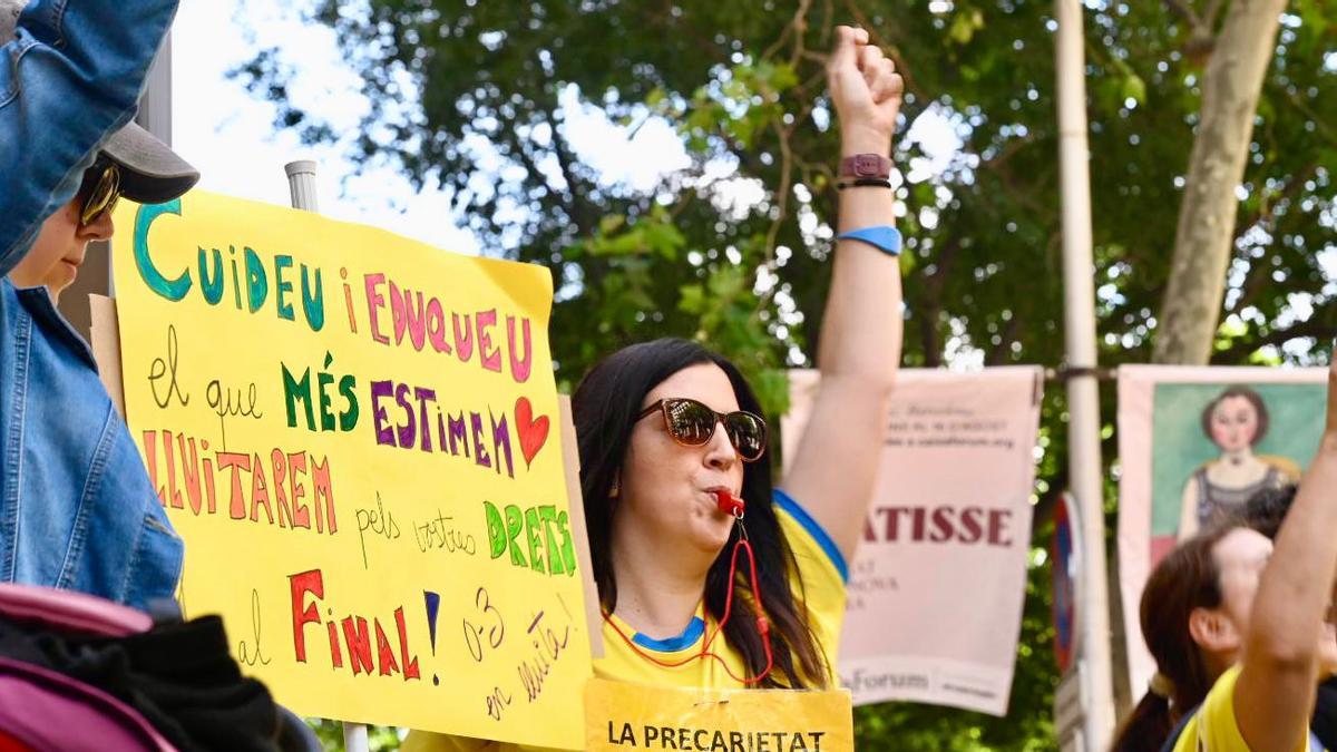 Una madre muestra una pancarta de apoyo a las educadoras, este jueves en Barcelona.