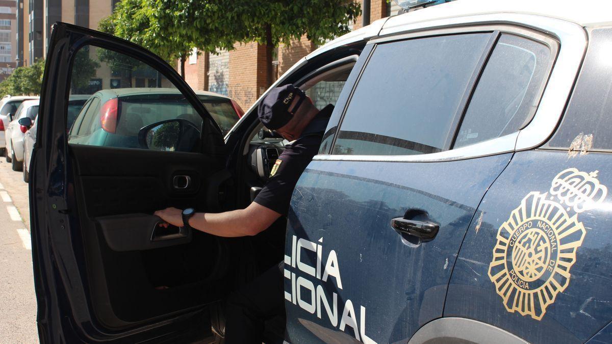 Un agente de la Policía Nacional entrando en el coche radiopatrulla