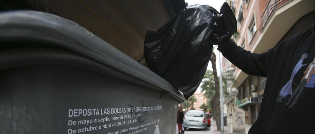 Una persona lanza basura a un contenedor en Alicante