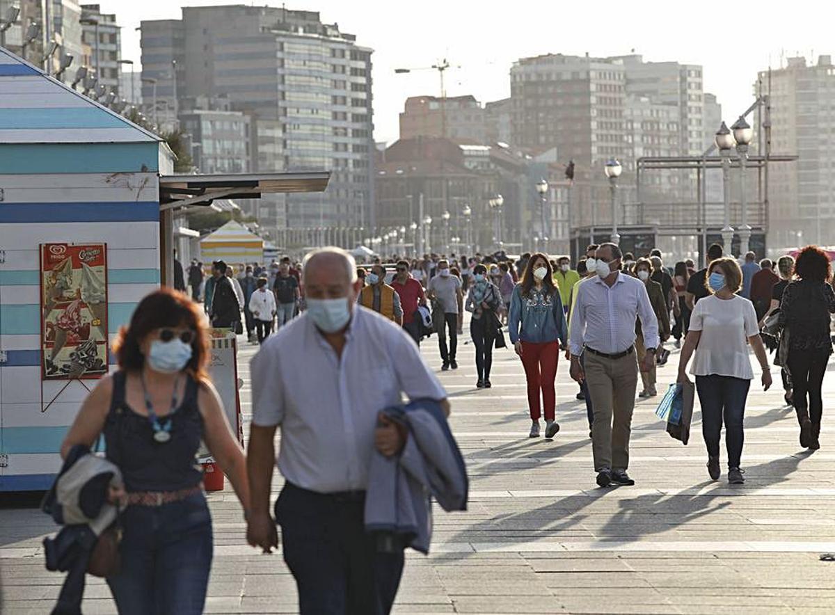 Gente pasea con mascarilla por Gijón. | Ángel González