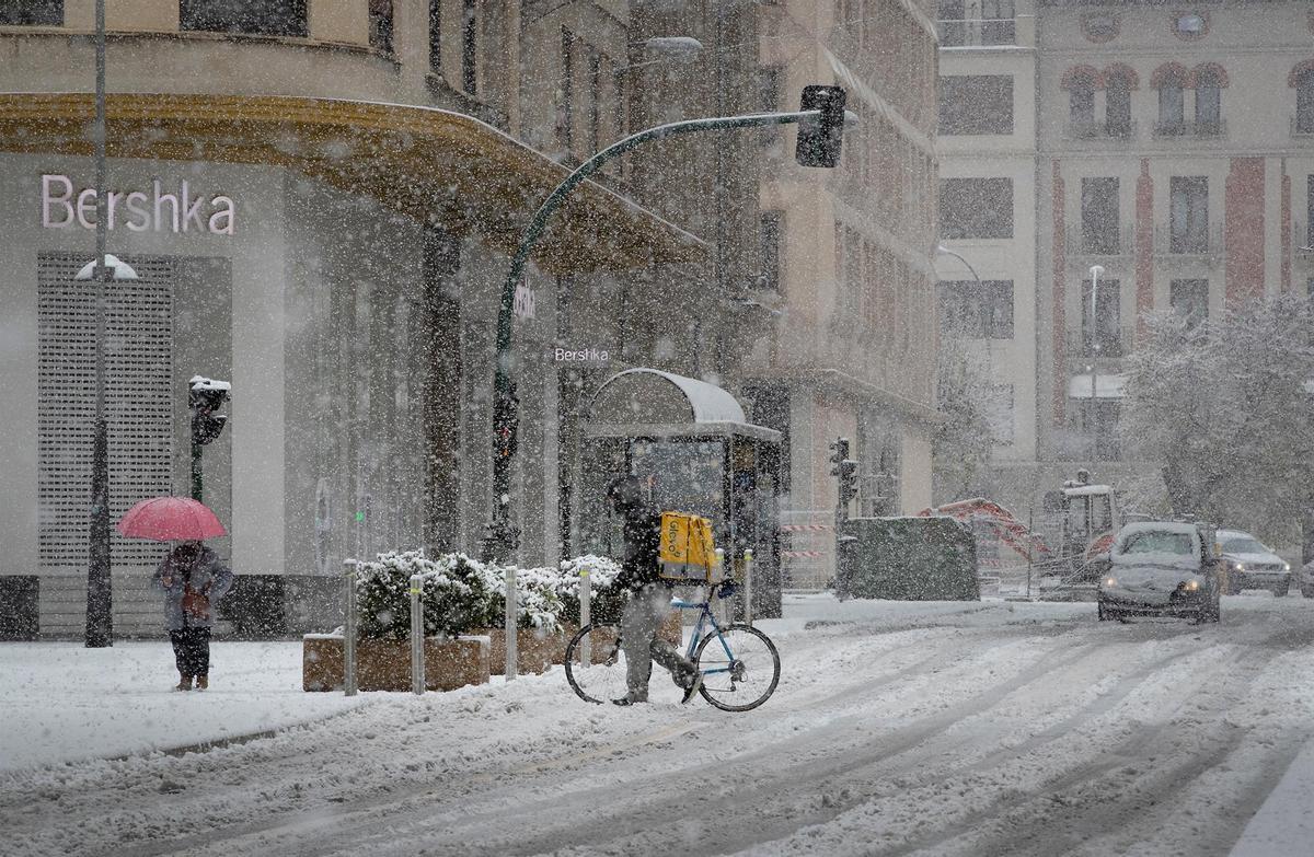 Un repartidor de comida a domicilio camina con su bicicleta por la calle Cortes de Navarra en Pamplona.