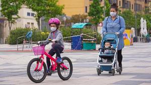 Madre pasea con su hija por Igualada, el primer dia que pueden salir los niños menores a la calle.