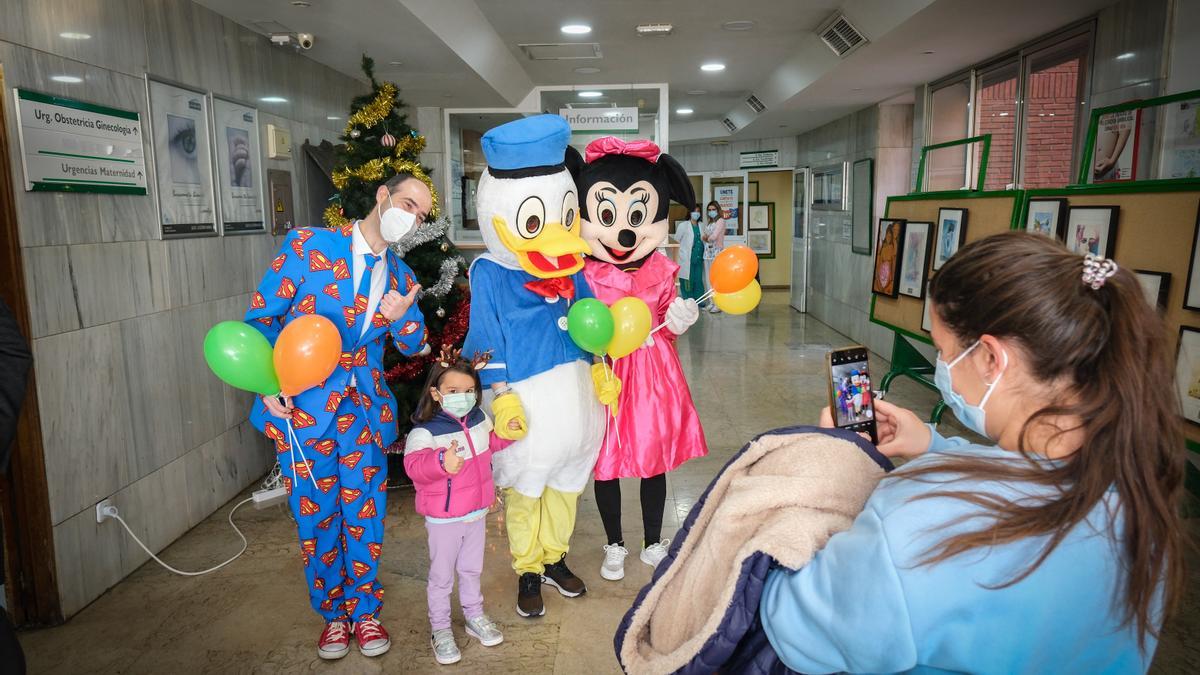 Llegada al hospital de Minnie, Donald y el mago, que posan con una niña para una foto.