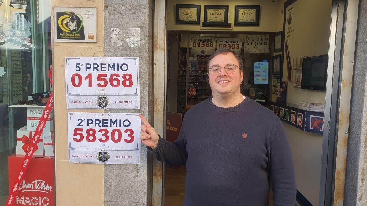 El propieario del estanco mostrando los premios de la Lotería de Navidad.