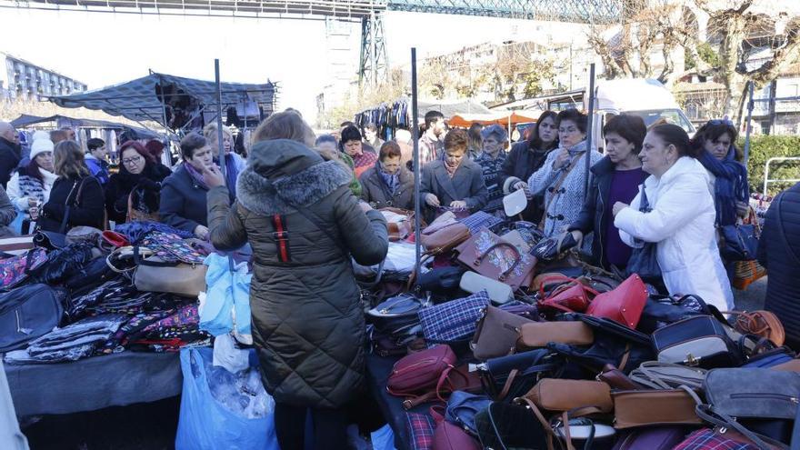 Unas personas observan la mercancía en uno de los puestos de la feria de Redondela, esta mañana. / Ricardo Grobas