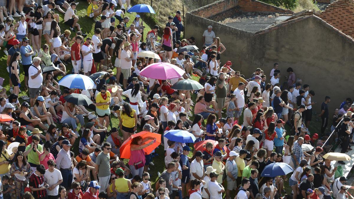 Público en los cuestos frente al toril en la salida de Galocho en 2025. Las gorras y los paraguas protegen del sol y el calor.