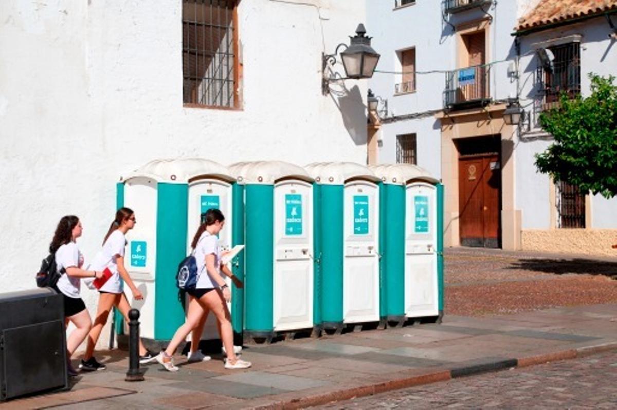 Vrias chicas pasan por delante de unos urinarios de Sadeco en Santa Marina.