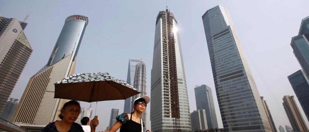 Ciudadanas chinas pasean ante varios rascacielos en la capital económica y financiera del país: Shangái.