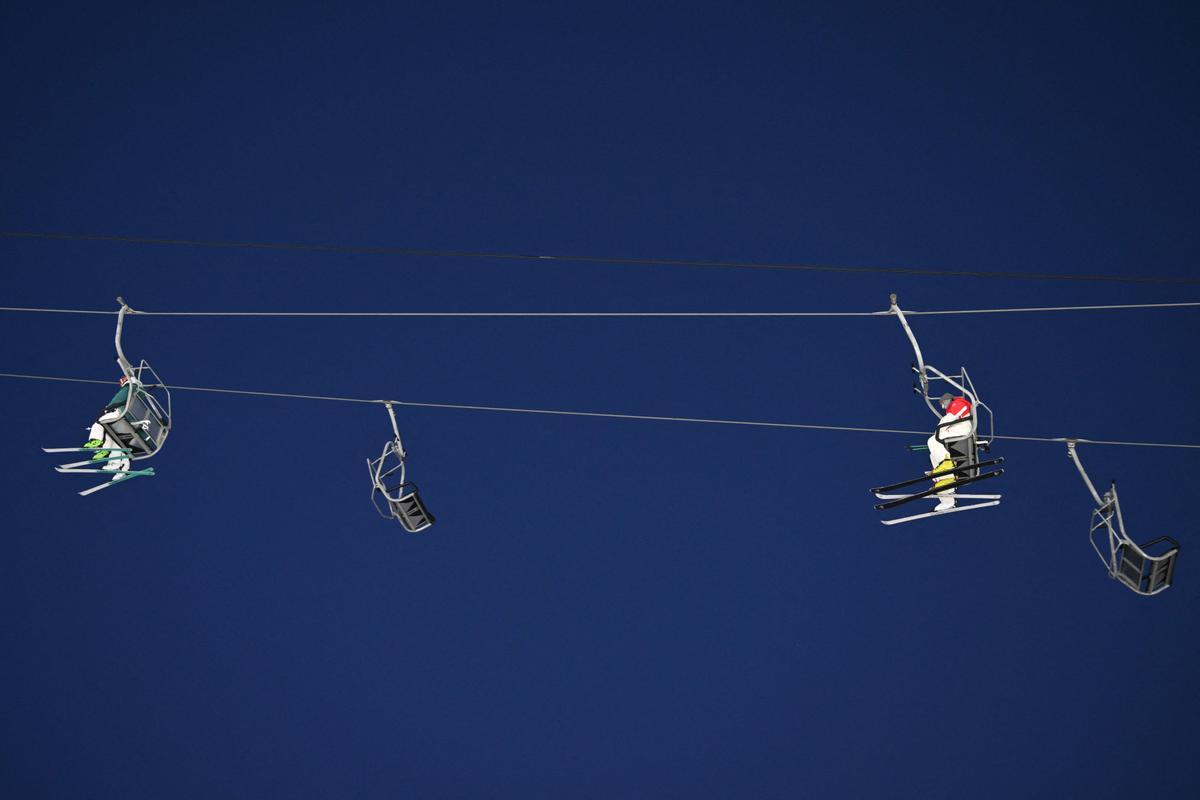 Atletas utilizan el remonte para subir a la montaña y participar en una sesión de entreno de esquí de estilo libre en modalidad ’mogul’, en el parque de nieve de Genting, en Zhangjakou.