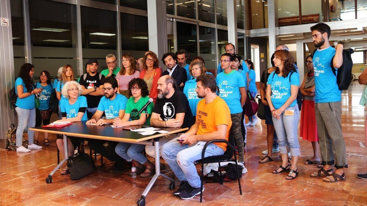 Miembros de las entidades sociales por el derecho a la vivienda y de los grupos municipales Barcelona en Comú, ERC y PSC, hoy en el vestíbulo del Ayuntamiento de Barcelona.