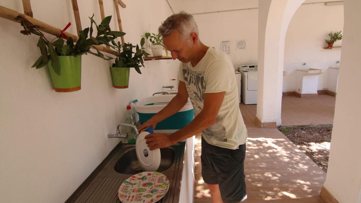 Miguel lava los platos en la zona de limpieza del cámping Los Villares.