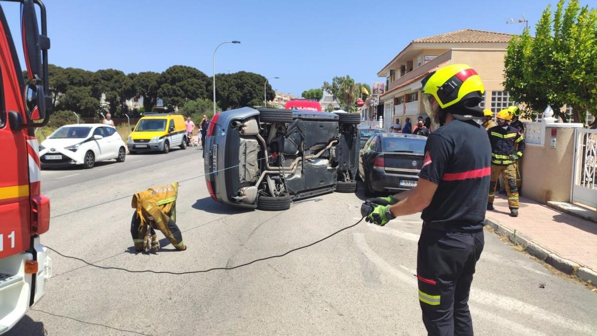 Rescate de un perro atrapado tras un accidente en el que el coche ha quedado volcado sobre la calzada en la urbanización Los Altos de Torrevieja