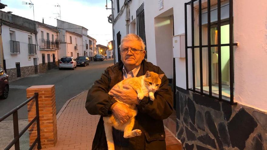 El cura posa en Torrejón el Rubio junto a su gato Menino.