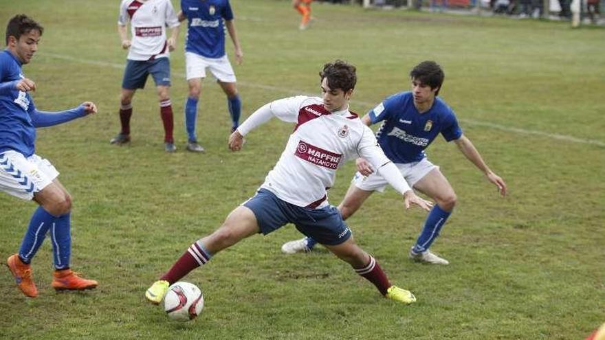 El fabril Cristian intenta controlar el balón ante la presión de dos futbolistas del Oviedo B.