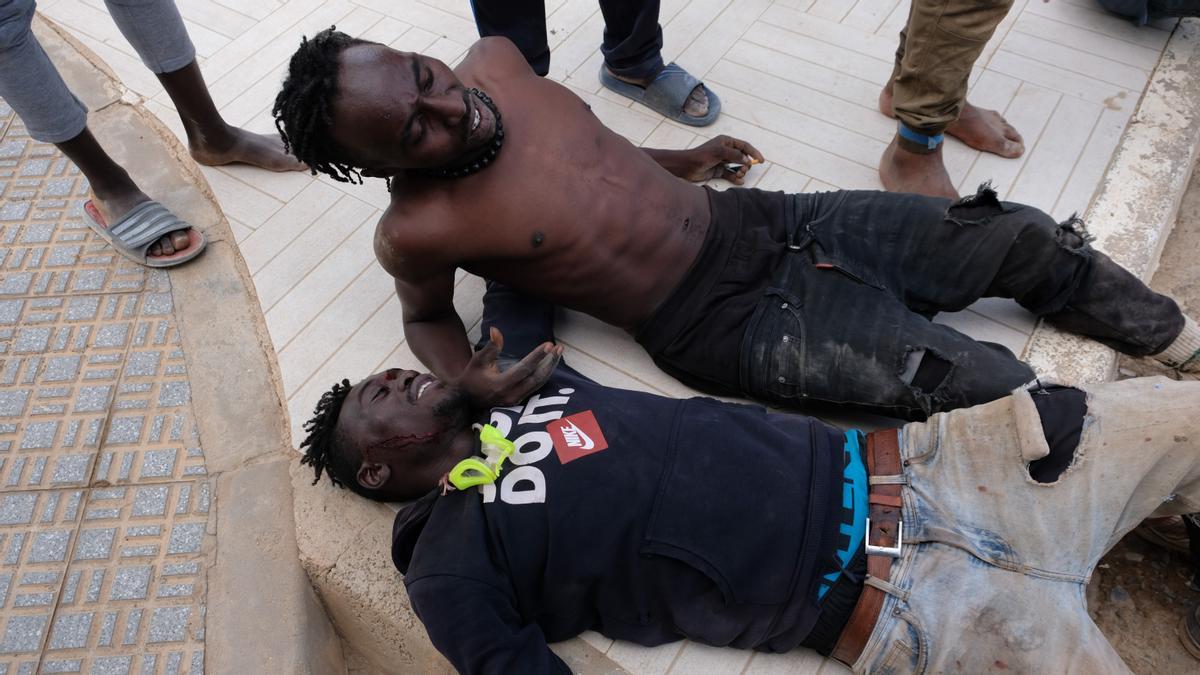 Dos migrantes heridos descansan tras saltar la valla de Melilla, a 24 de junio de 2022, en Melilla