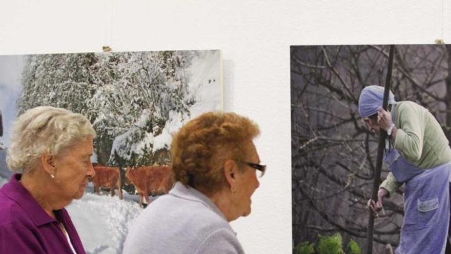 Dos mujeres observan algunas de las fotografías de la muestra en La Calzada.