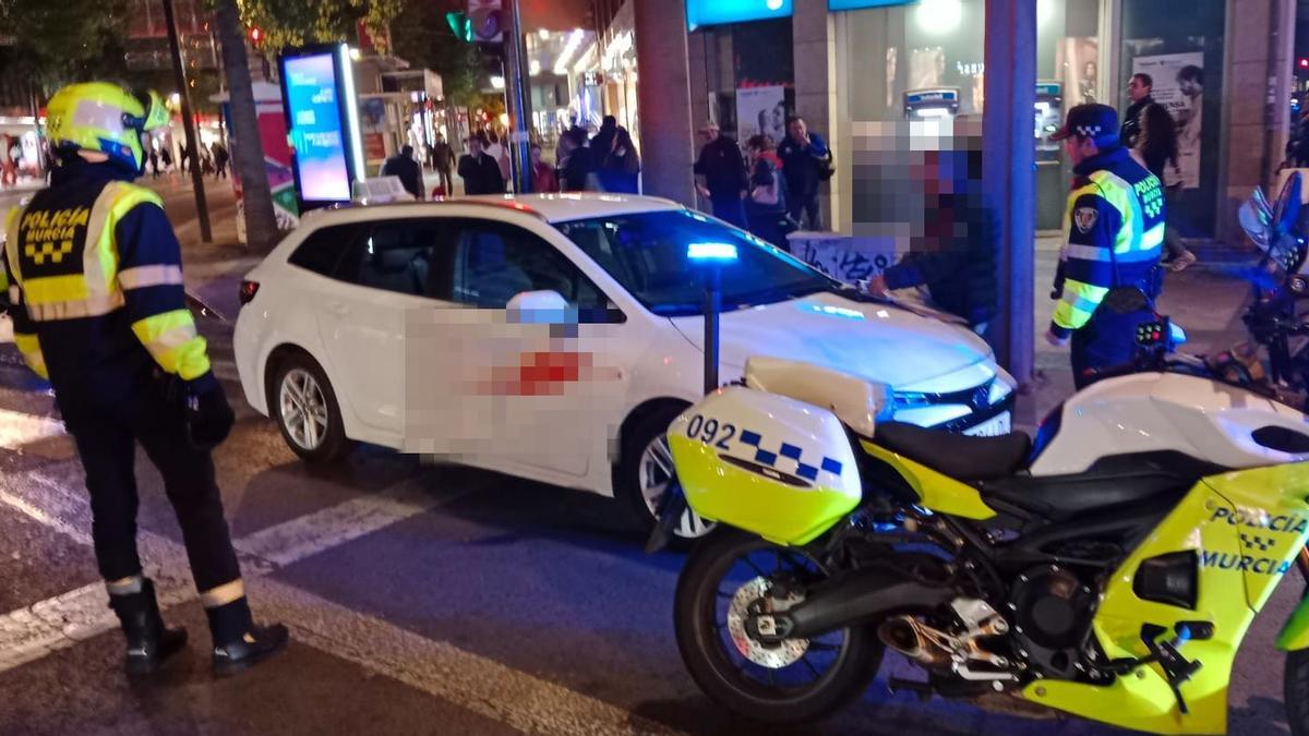 Agentes de la Policía Local de Murcia, junto al taxi cuyo conductor fue sorprendido ebrio al volante.