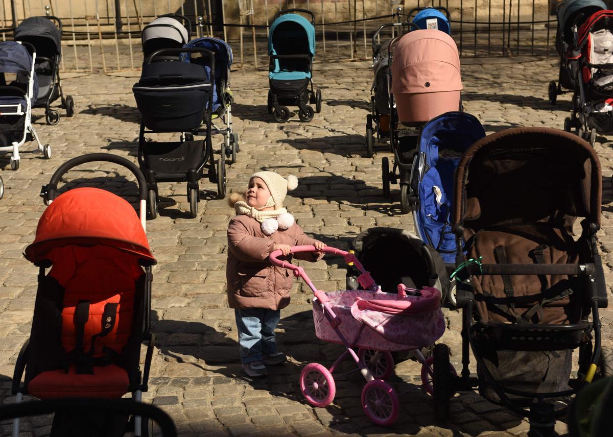 Un niño entre el más de un centenar de carritos de bebé que se han colocado hoy frente al ayuntamiento de Leópolis para llamar la atención sobre el gran número de niños que están muriendo en la guerra.