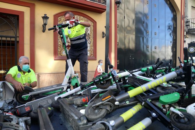 Operarios municipales cargando con patinetes de alquiler.