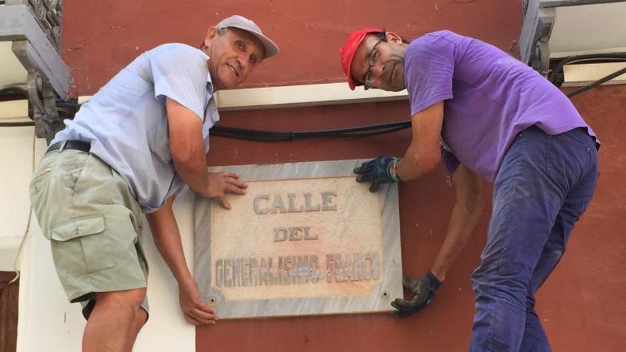 Dos trabajadores retiran la placa de la antigua calle del Generalísimo.