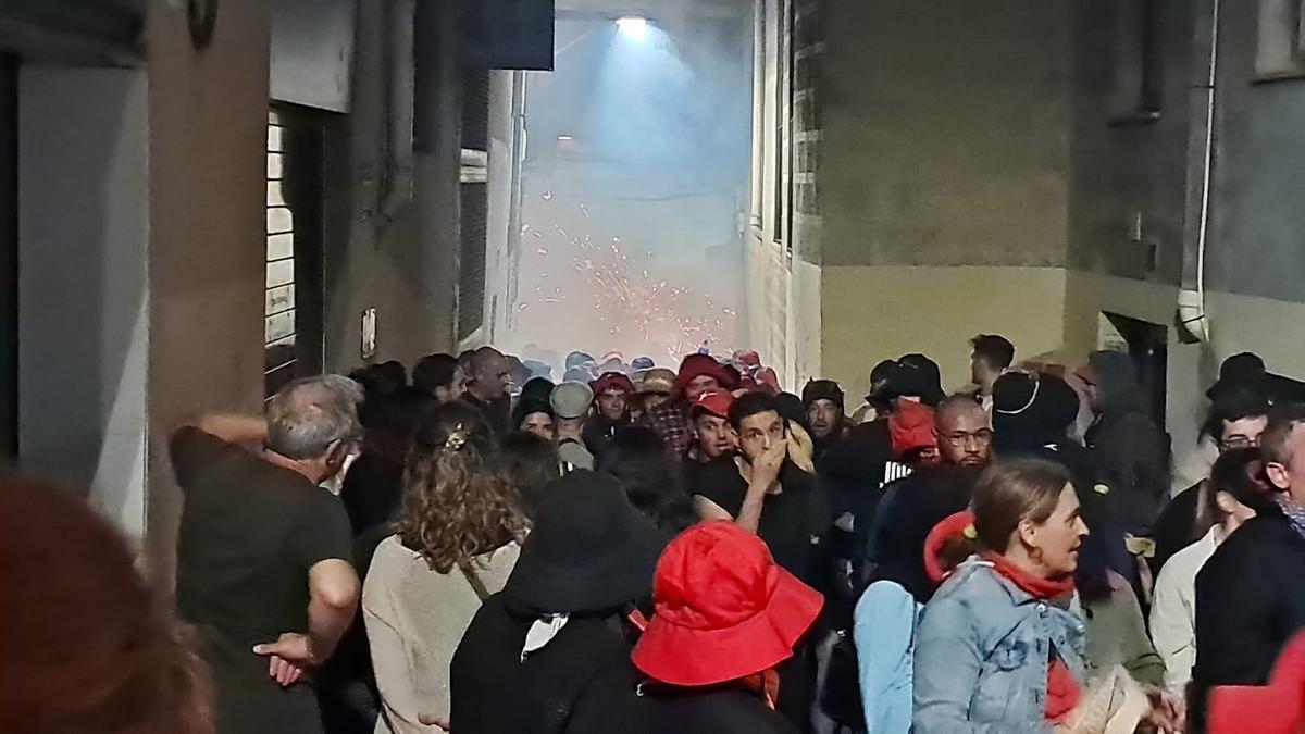 Un gruix de persones contempla el Correfoc des de la distància al carrer Sant Miquel