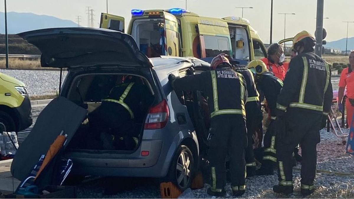 Bomberos trabajan en el rescate de los pasajeros del turismo que han quedado atrapados en el accidente.