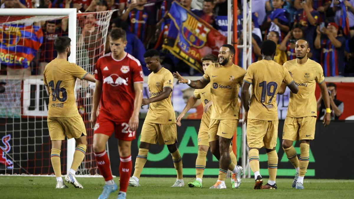 Memphis Depay, al mig i somrient, rep la felicitació després d’un gol a la pretemporada.  | EFE/JASON SZENES