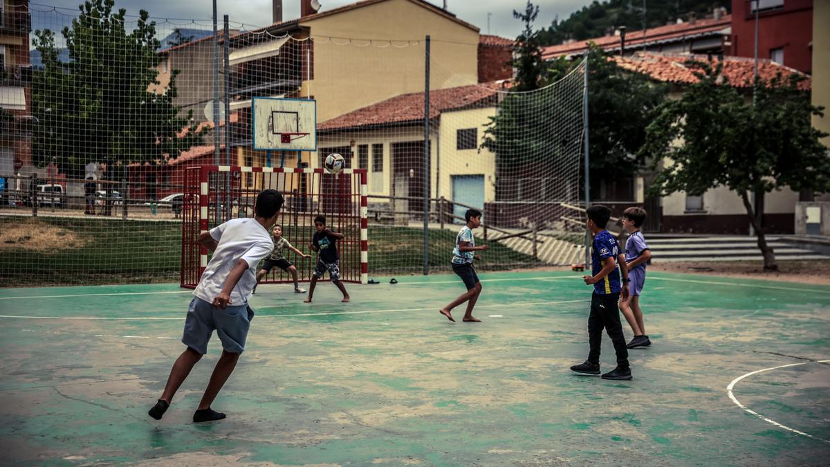 Niños de entornos migrantes juegan a fútbol en una plaza de Ripoll.