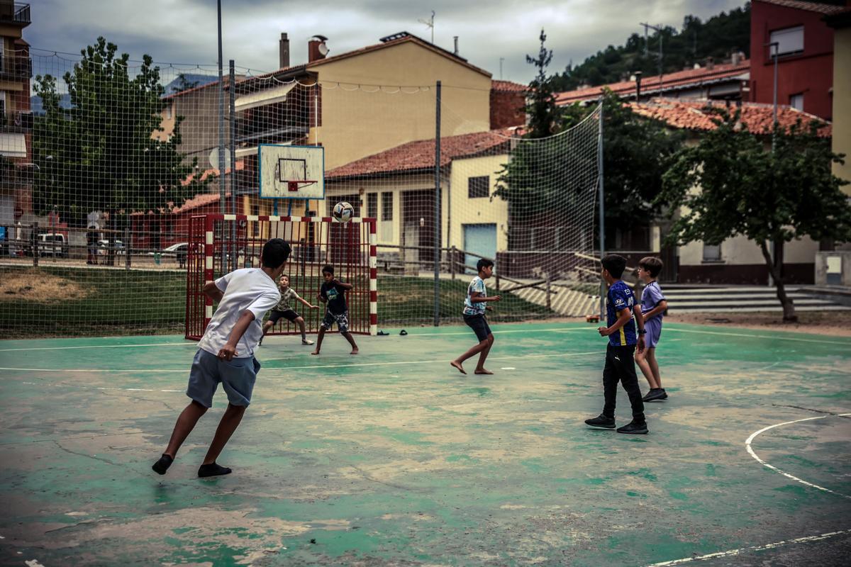 Niños de entornos migrantes juegan a fútbol en una plaza de Ripoll.