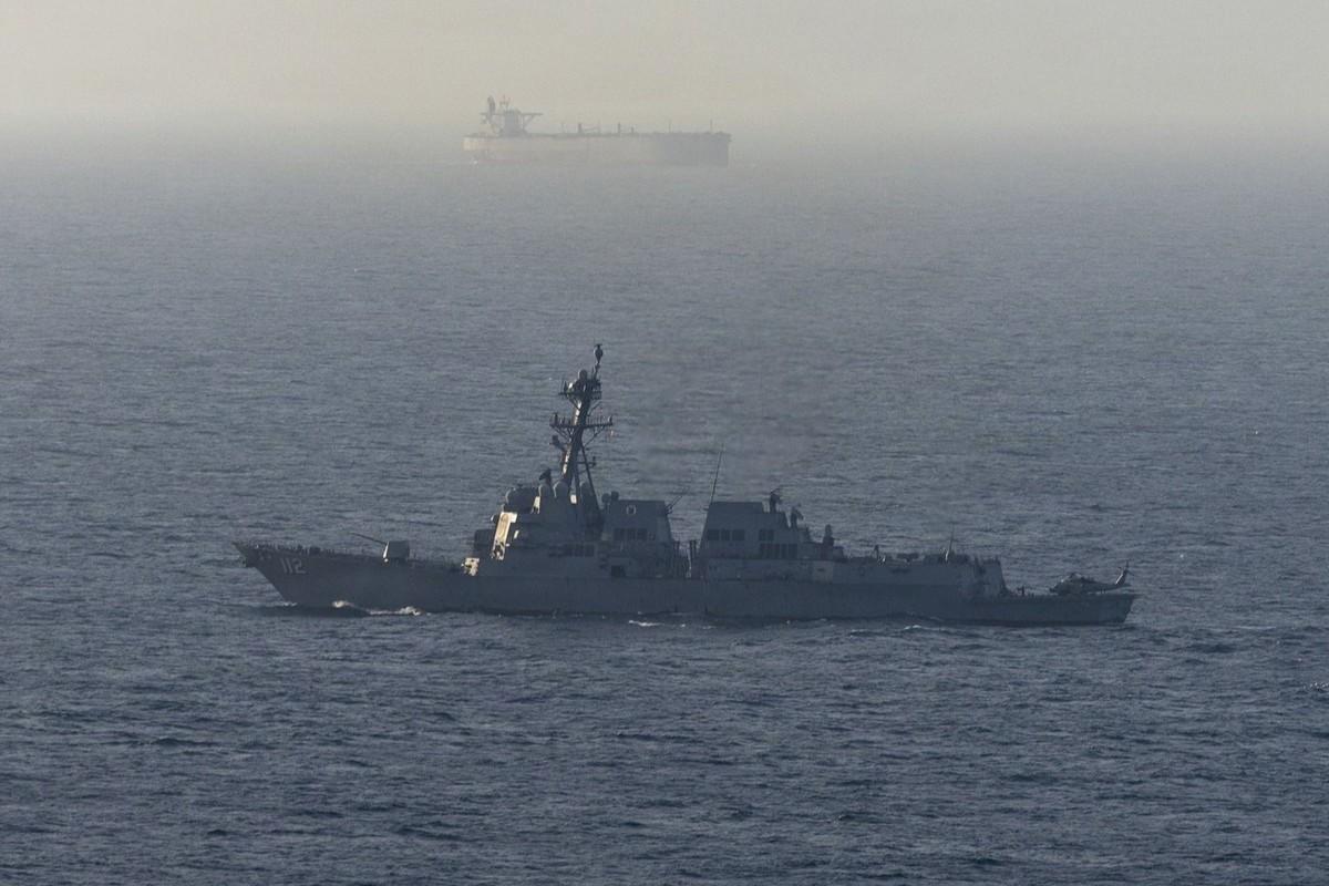 Un buque de guerra patrulla por el estrecho de Ormuz. Al fondo, un petrolero fondeado.