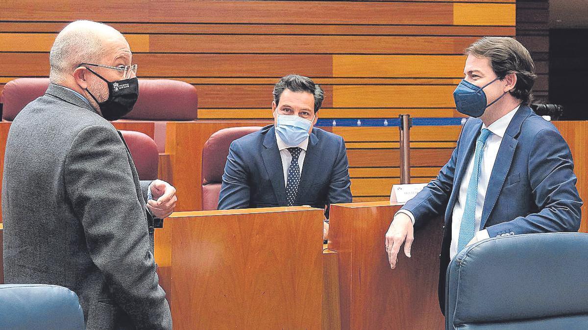 El presidente Mañueco, y el vicepresidente, Francisco Igea, conversan con el portavoz del Grupo Popular, Raúl de la Hoz, durante el pleno de las Cortes.