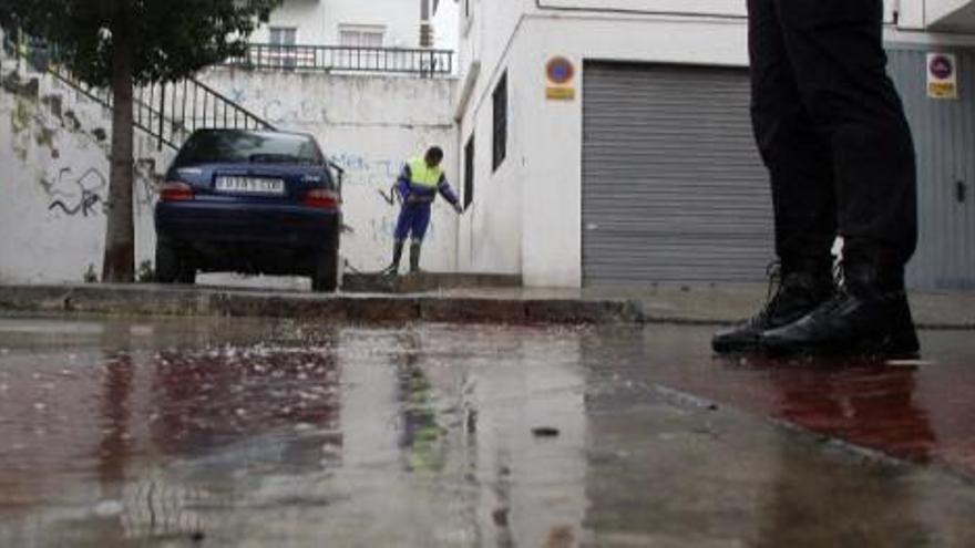 Un operario limpia la sangre de la víctima, en presencia de un policía.