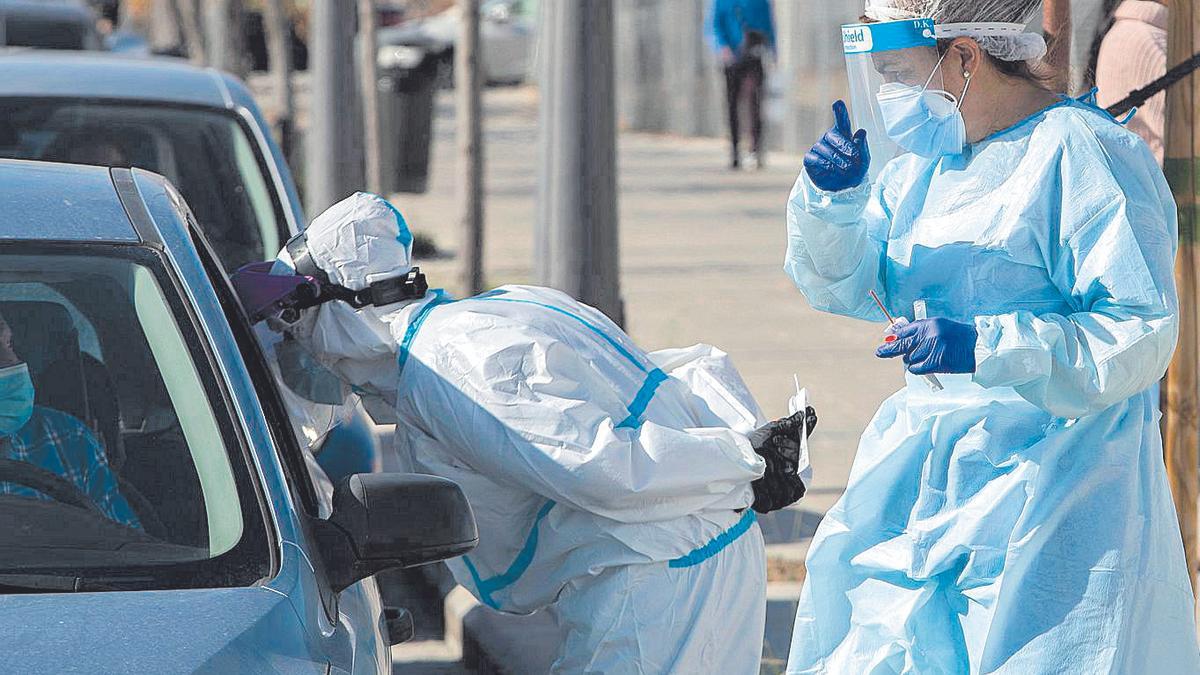 Dos sanitarios hacen pruebasPCR desde el coche en el hospital La Fe, este lunes.