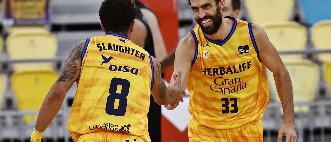 Javier Beirán (33) saluda a su compañero A.J. Slaughter tras una canasta, en el choque del pasado fin de semana en el Arena contra el Joventut. | | ACB PHOTO/M. HENRÍQUEZ