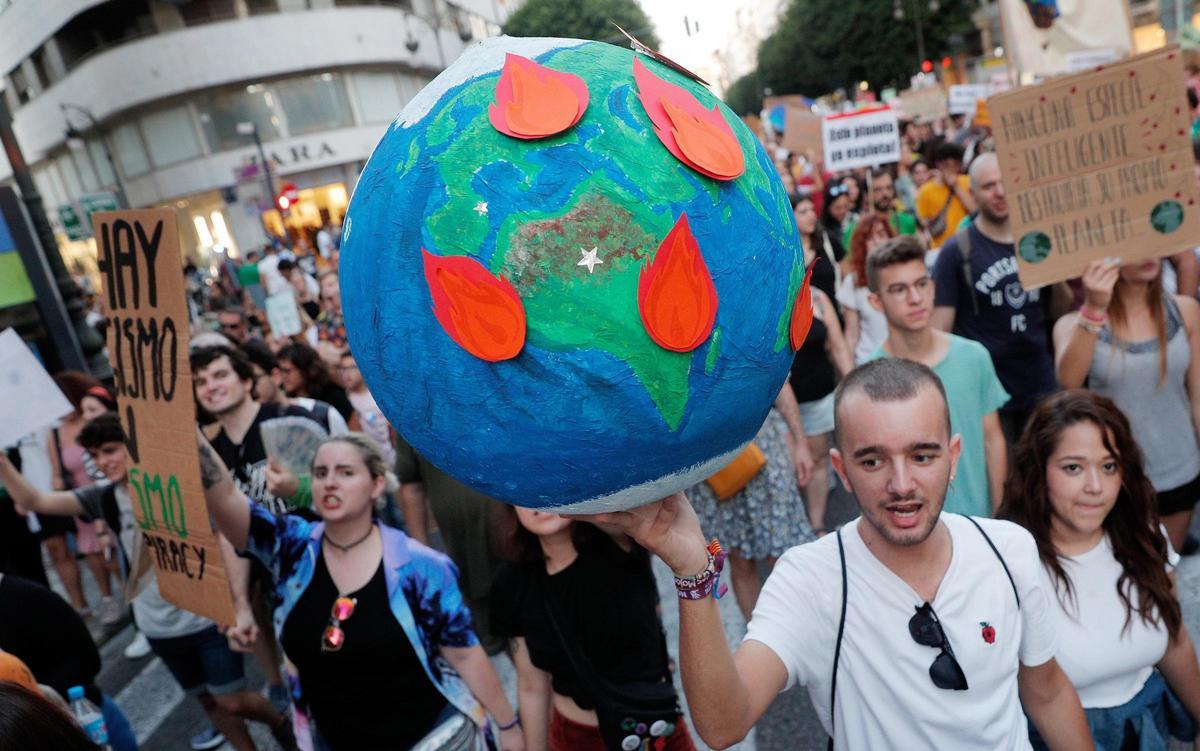 Un joven lleva globo terrestre en llamas durante una manifestación celebrada en Valencia por la emergencia climática y la lucha para que se tomen medidas urgentes para evitar el cambio climático.