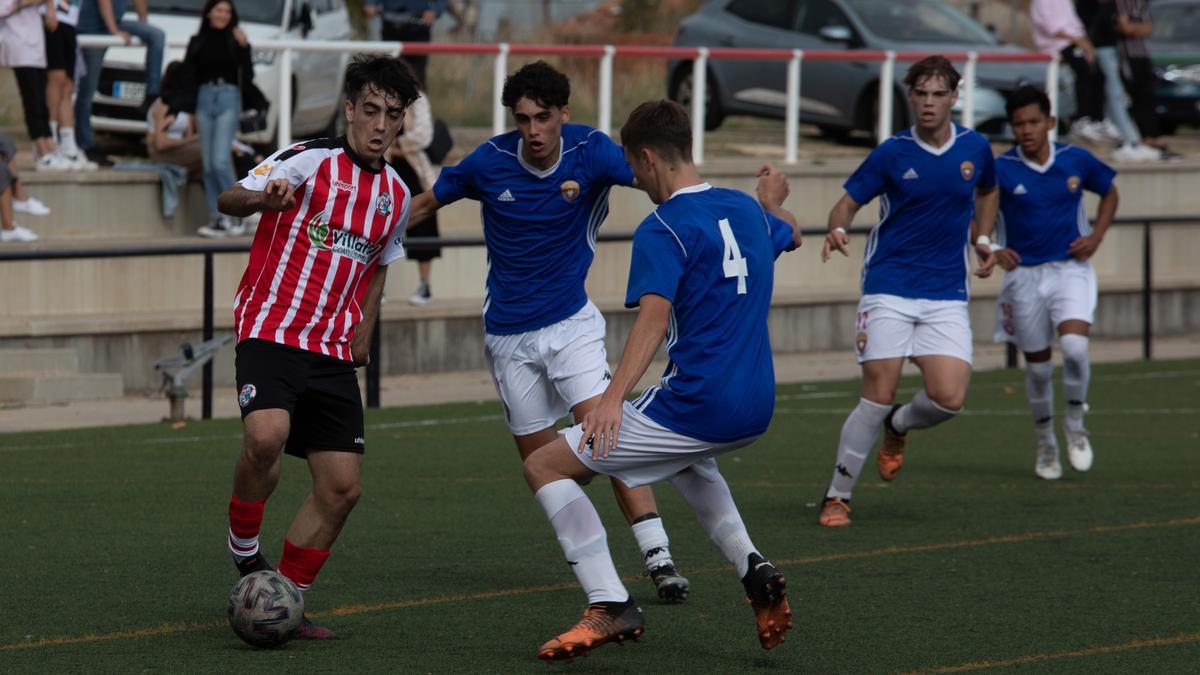 Un jugador del Zamora CF juvenil trata de superar a varios defensores del CD Isoba